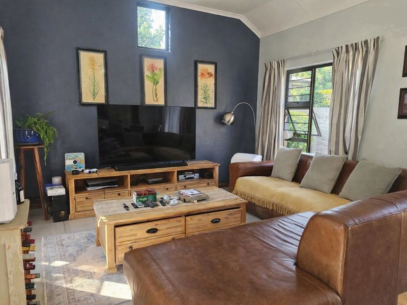A comfortable living room featuring a vaulted ceiling, tiled flooring, and large windows that provide natural light.