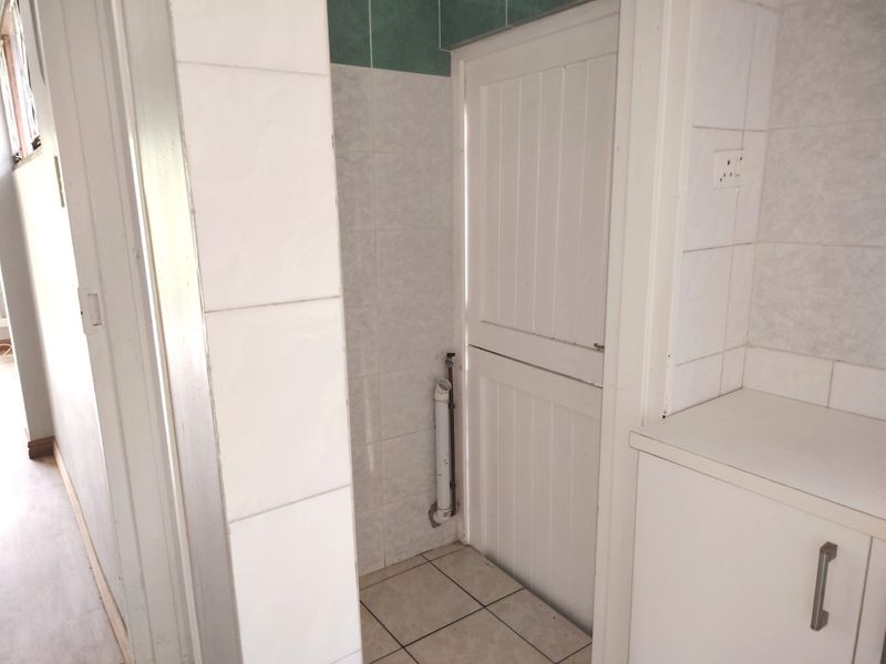 A functional laundry area featuring tiled walls and flooring, built-in cabinetry, and dedicated plumbing connections for laundry appliances.