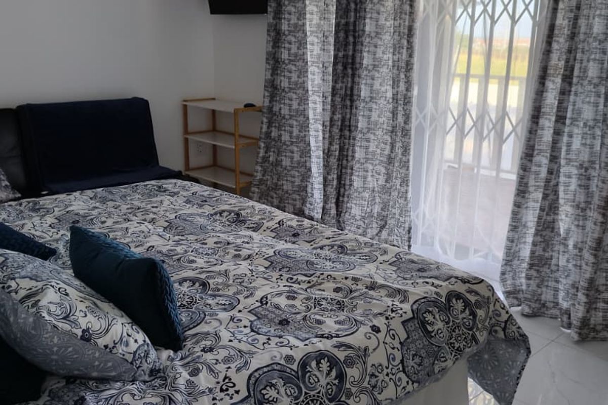 A bedroom featuring tiled flooring and a security gate leading to an outdoor area.
