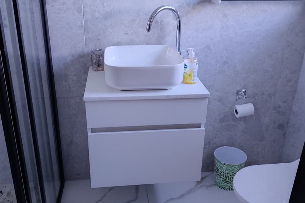 Modern bathroom featuring a wall-mounted vanity with a vessel sink, chrome fixtures, a glass shower enclosure, and contemporary tiled finishes.