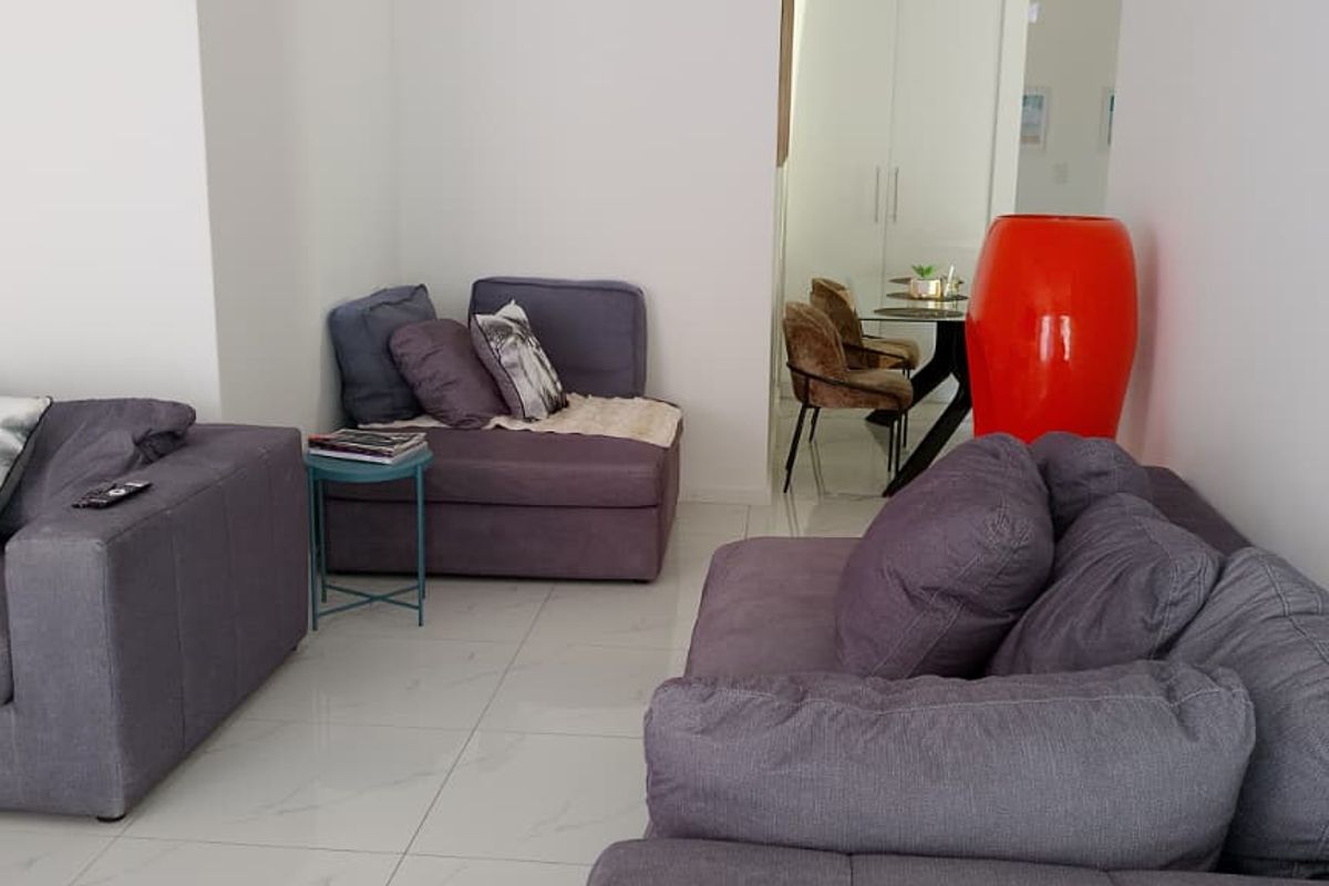 A bright living area featuring polished tiled flooring and a neutral color palette, providing a clean and open space for relaxation.