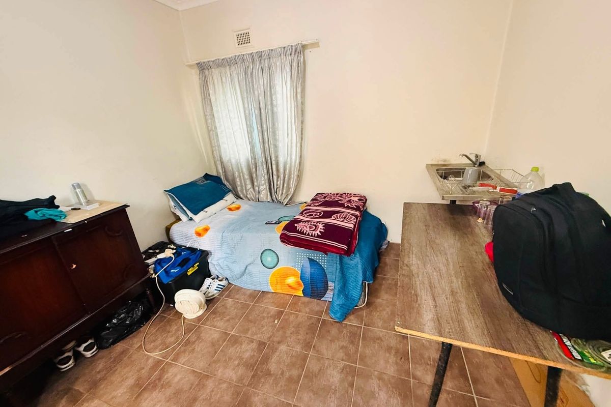 A bedroom featuring tiled flooring and a small built-in sink area, requiring cosmetic updates to improve the overall condition.