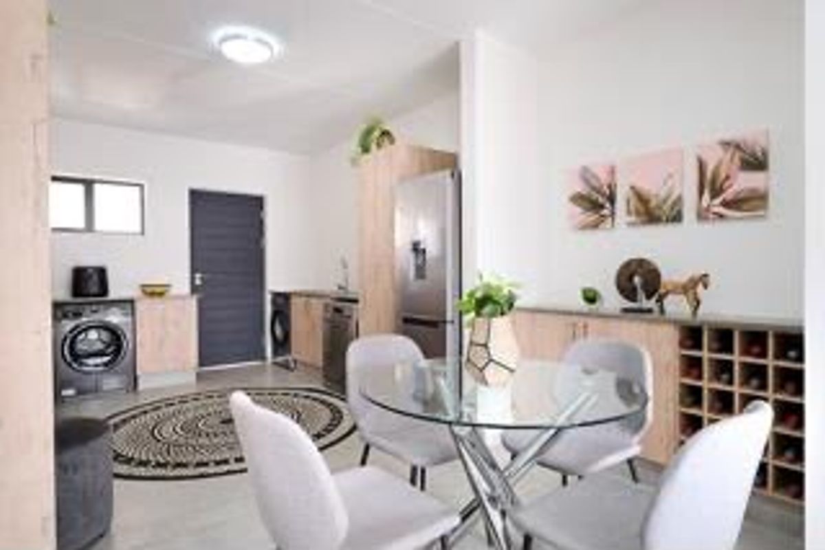 An open-plan living and dining area featuring modern light wood cabinetry, a built-in wine rack, and tiled flooring throughout.