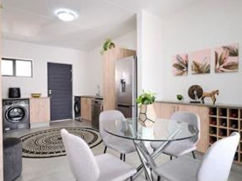 An open-plan living and dining area featuring modern light wood cabinetry, a built-in wine rack, and tiled flooring throughout.