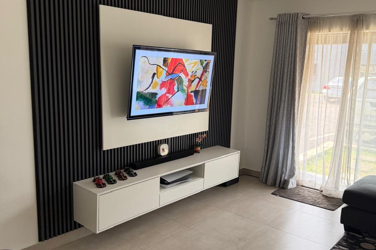 Modern living room featuring a stylish black slatted feature wall, floating media console, large format floor tiles, and direct access to an outdoor area.