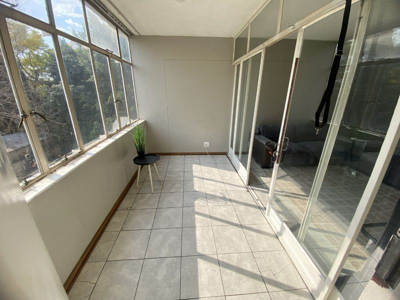 Enclosed balcony or sunroom featuring tiled flooring, large windows, and sliding glass doors, offering a bright and versatile space.