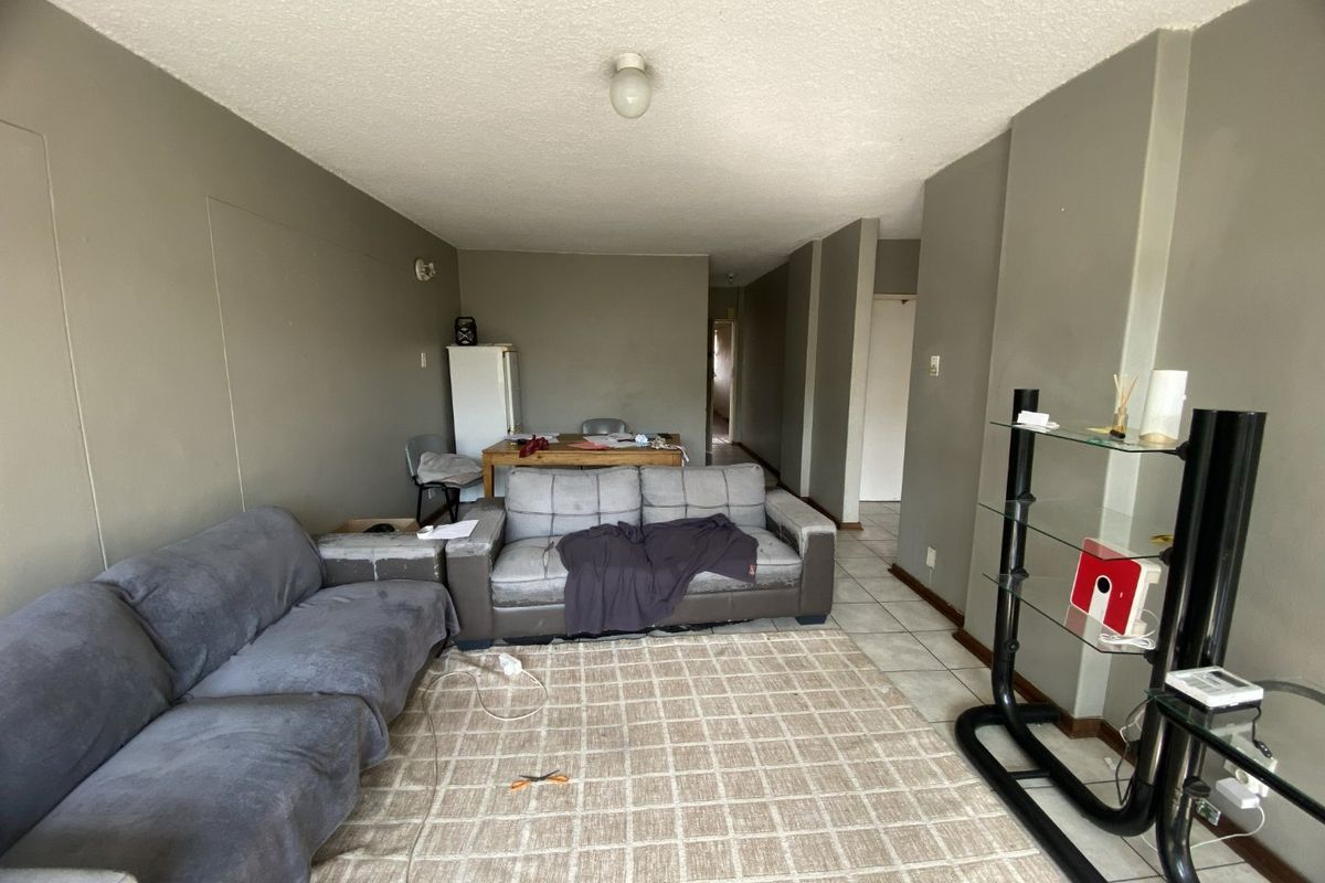 A spacious living area featuring tiled flooring and neutral wall tones, offering a blank canvas for potential interior updates and modernization.