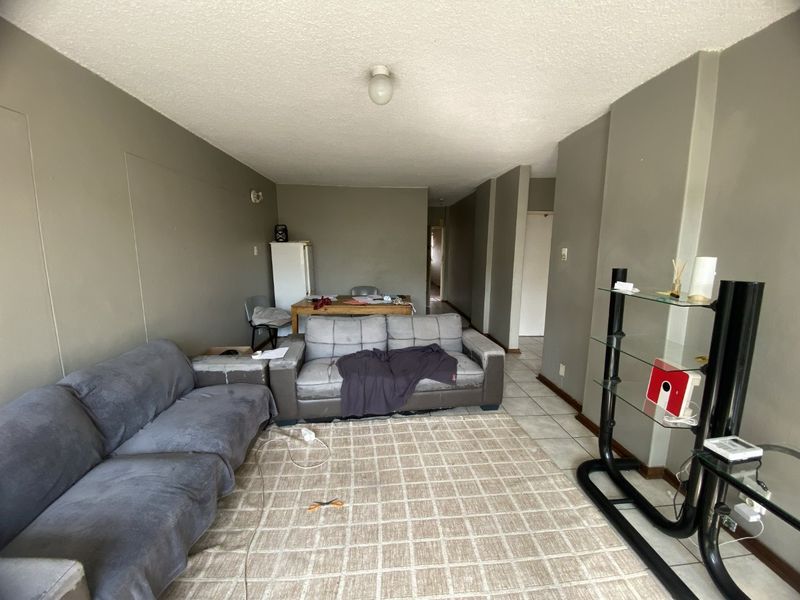 A spacious living area featuring tiled flooring and neutral wall tones, offering a blank canvas for potential interior updates and modernization.