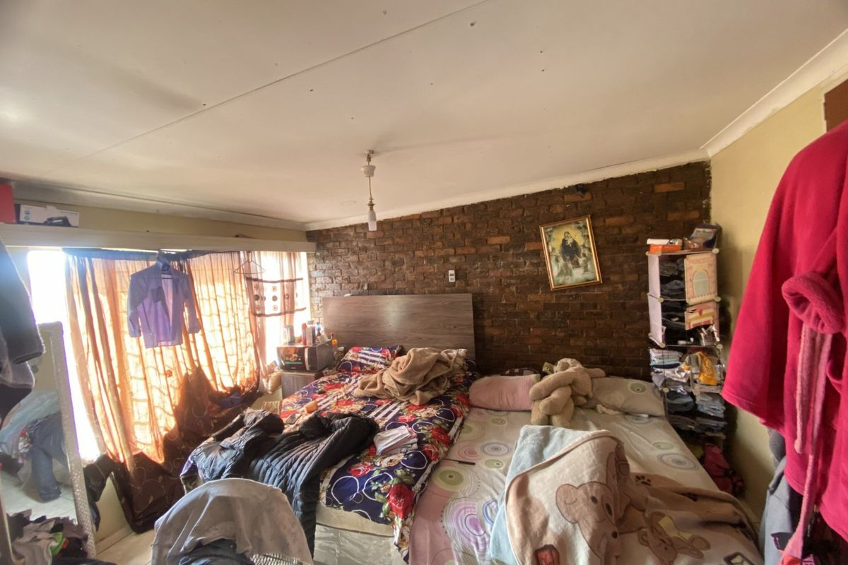 Bedroom featuring an exposed brick feature wall and standard ceiling finishes, requiring cosmetic updates to improve the overall aesthetic and condition.