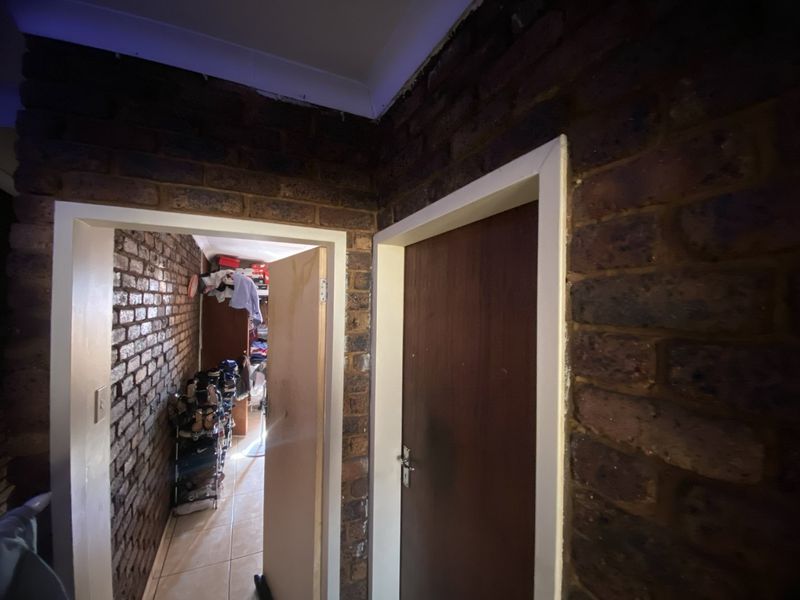 A hallway featuring exposed brick walls and timber doors, requiring minor finishing work at the ceiling junction.