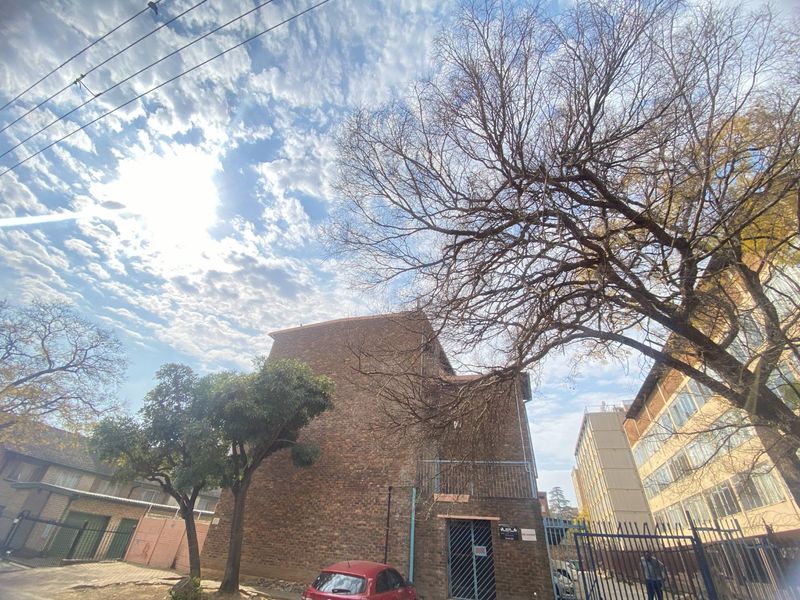 Rear view of the apartment building featuring a brick facade, metal security gate, and balcony access.