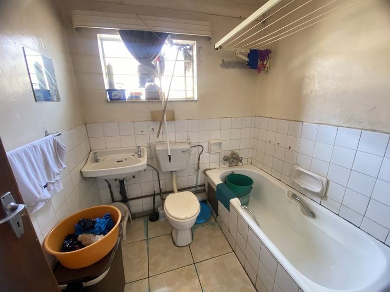 A dated bathroom featuring a standard bathtub, pedestal basin, and toilet, requiring significant renovation and cosmetic updates to improve its condition and functionality.