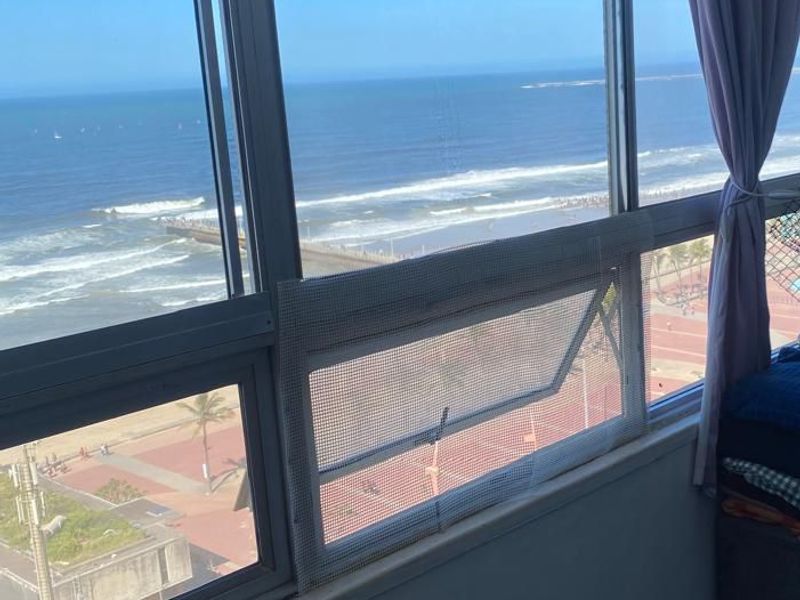A bright interior space featuring large windows with expansive, unobstructed views of the ocean and beachfront promenade.