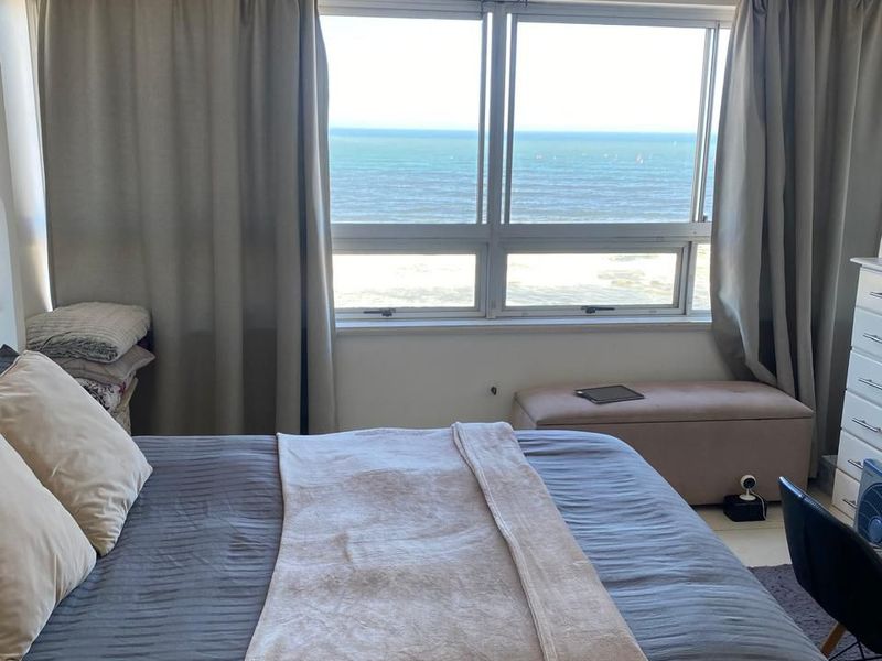A bedroom featuring a large window with direct ocean views and integrated curtain tracks.