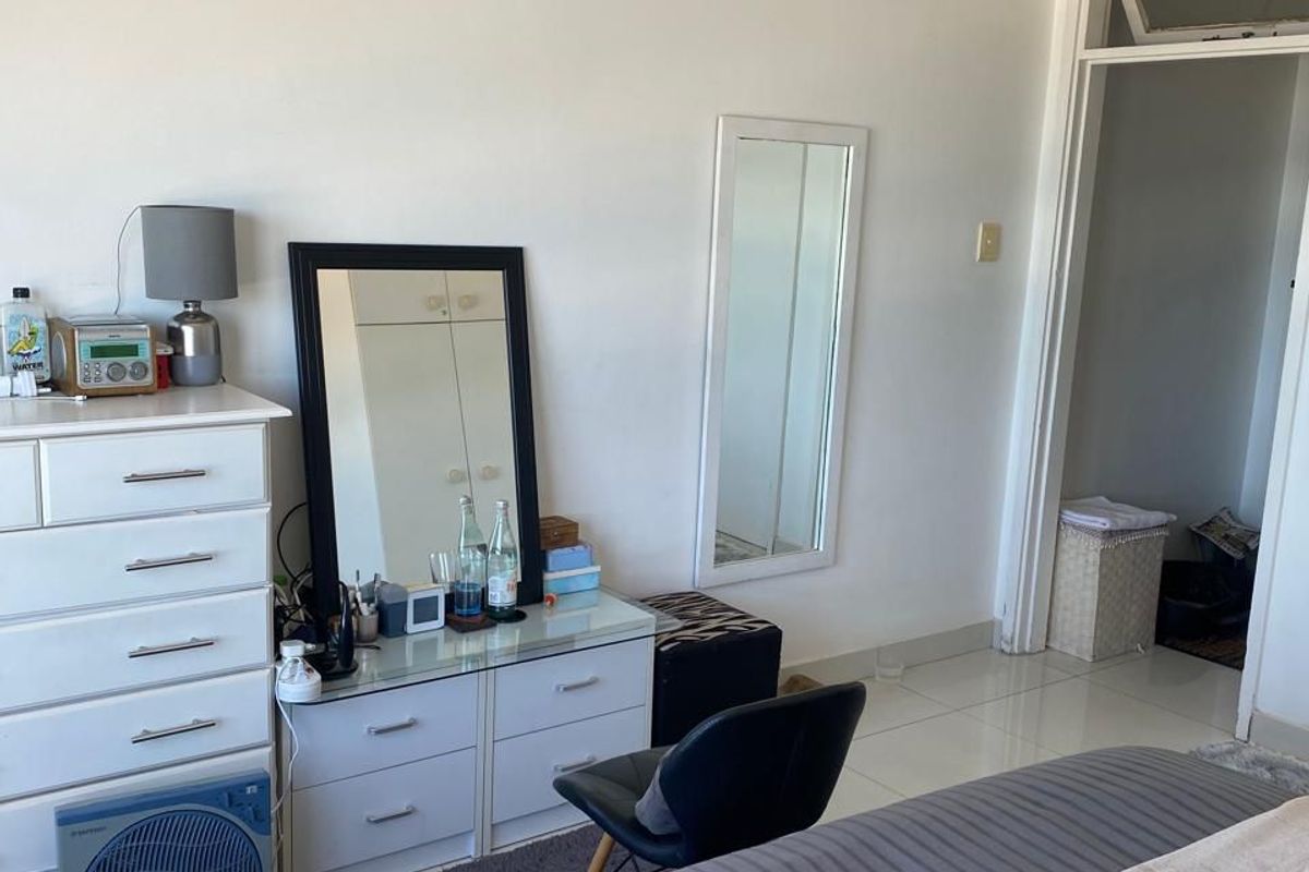 A bedroom featuring tiled flooring and a doorway with a transom window, providing a functional and neutral living space.