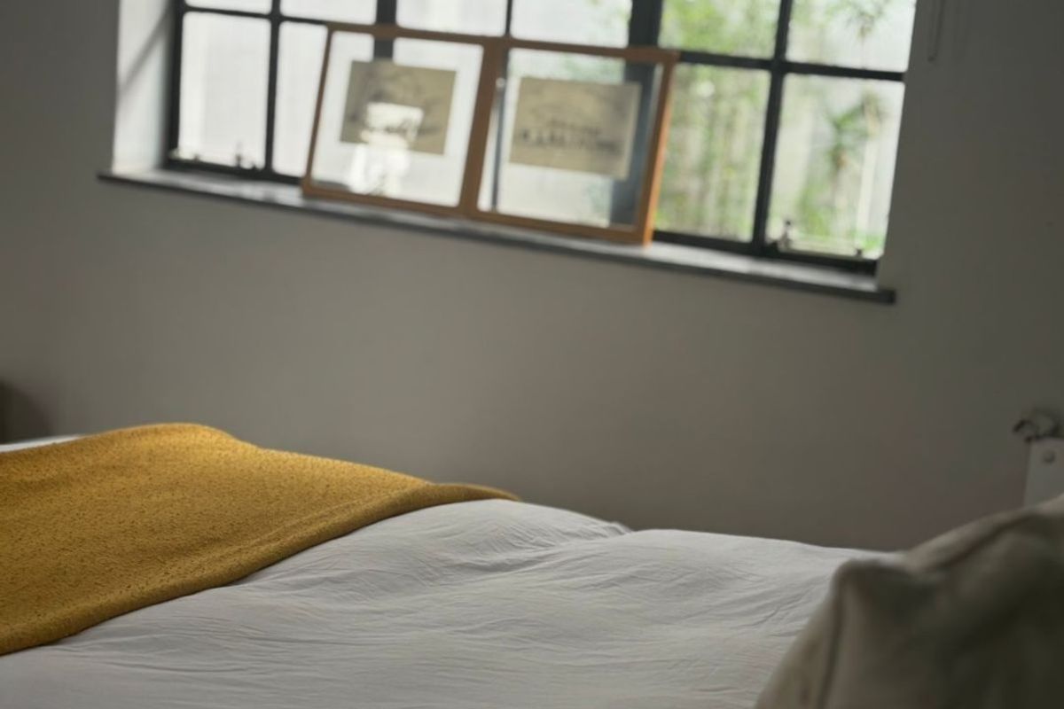 A bedroom featuring a large industrial-style steel-framed window that allows natural light into the space.