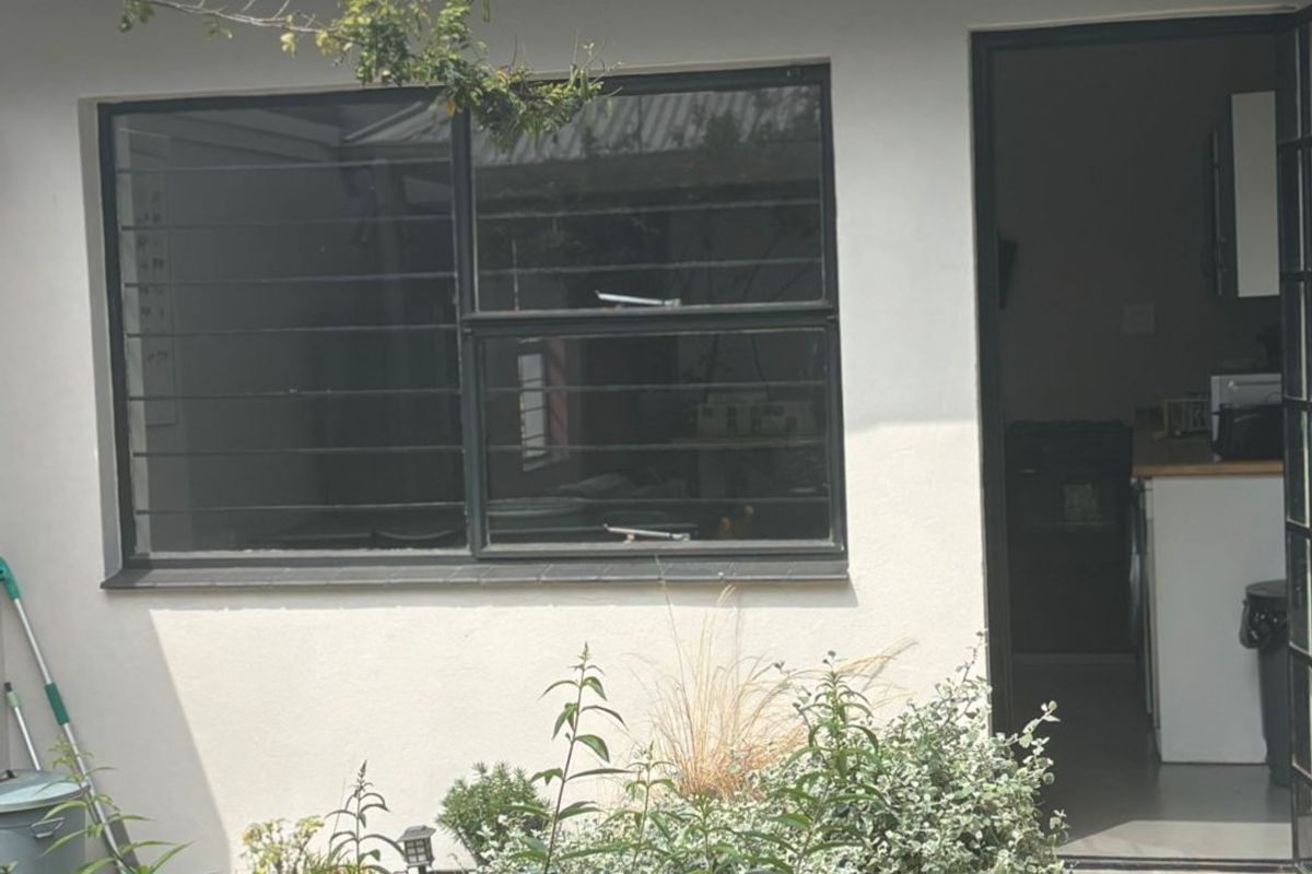 Rear exterior view of the property featuring a corrugated metal roof, security-barred window, and access door leading into the interior living space.