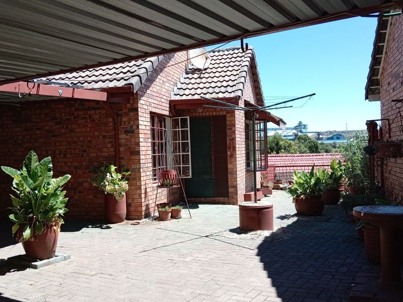 A covered outdoor patio area featuring brick construction, paved flooring, and a metal roof structure, providing a functional space for outdoor living.