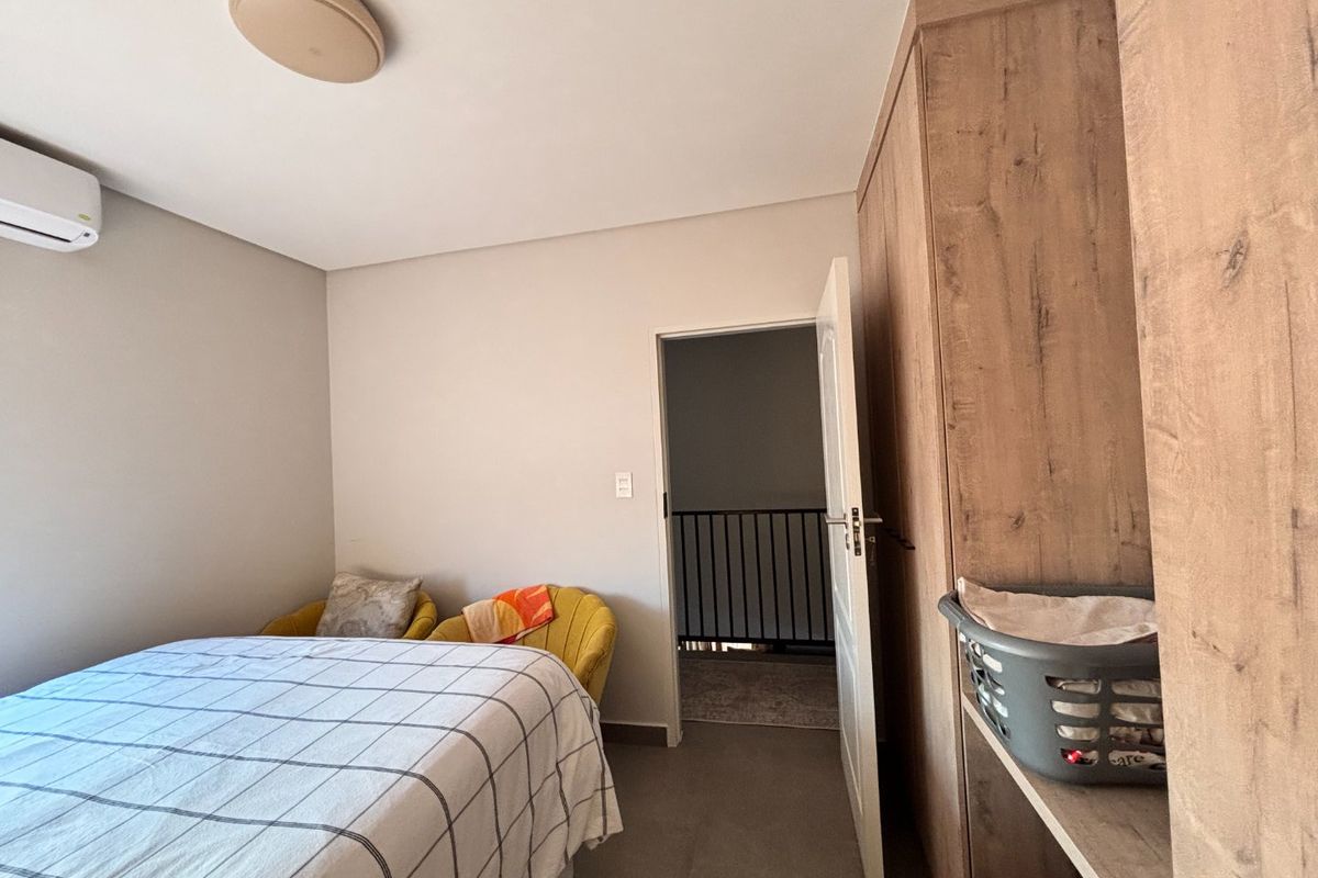 A well-maintained bedroom featuring a built-in wardrobe, split-system air conditioning, and neutral finishes, providing a comfortable and functional living space.