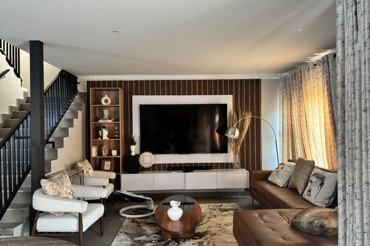Modern living room featuring a striking slatted timber feature wall with a built-in media unit and an adjacent staircase with a sleek metal balustrade.