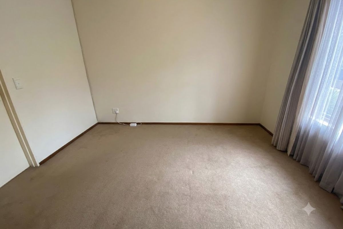 A clean, empty bedroom featuring neutral wall paint, carpeted flooring, and existing curtain tracks, providing a blank canvas for personalization.