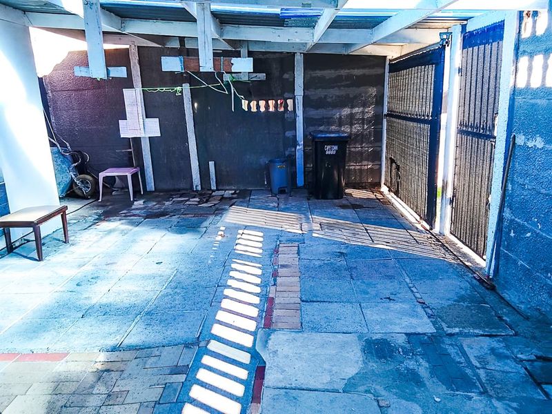 A covered outdoor patio area featuring paved flooring and a timber roof structure, providing a functional space for outdoor utility or entertainment.