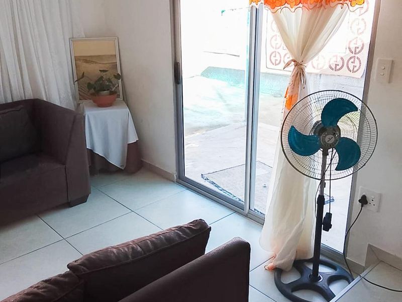A living room featuring ceramic floor tiles and a sliding glass door providing access to the outdoor area.