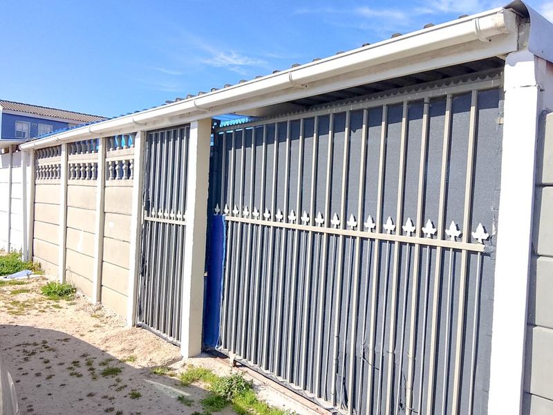 A secure perimeter wall featuring a sliding metal gate and integrated guttering system, providing privacy and security for the property frontage.