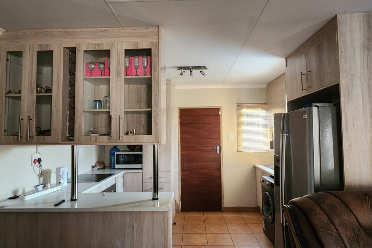 A functional kitchen featuring light wood-look cabinetry, a breakfast bar, tiled flooring, and integrated appliance space.