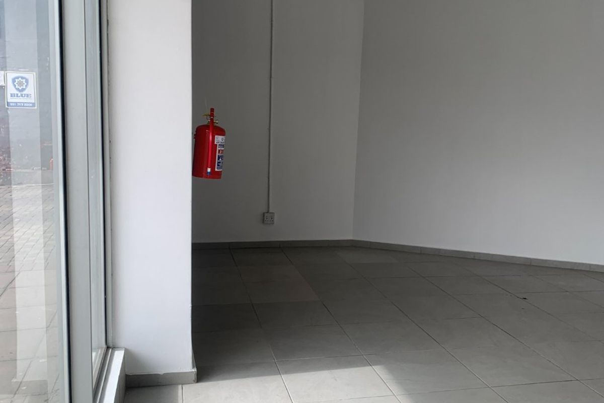 An empty commercial office space featuring large glass windows, tiled flooring, and a suspended ceiling with integrated lighting.
