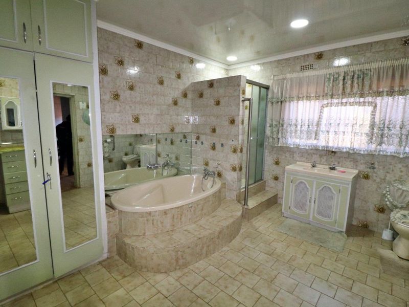 Spacious bathroom featuring a built-in bathtub, separate shower enclosure, dual vanity, and extensive built-in cabinetry with dated finishes.