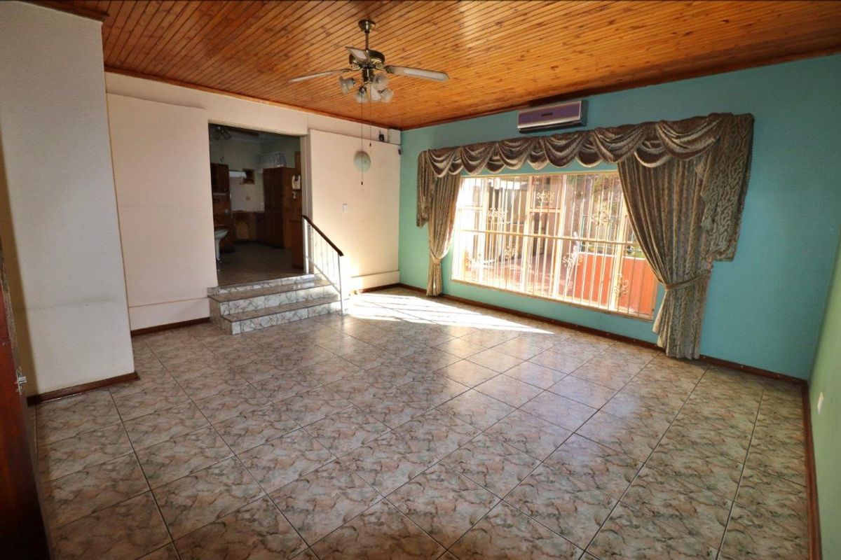 Spacious living area featuring timber ceiling, ceramic tiled flooring, split system air conditioning, and large window with security bars.