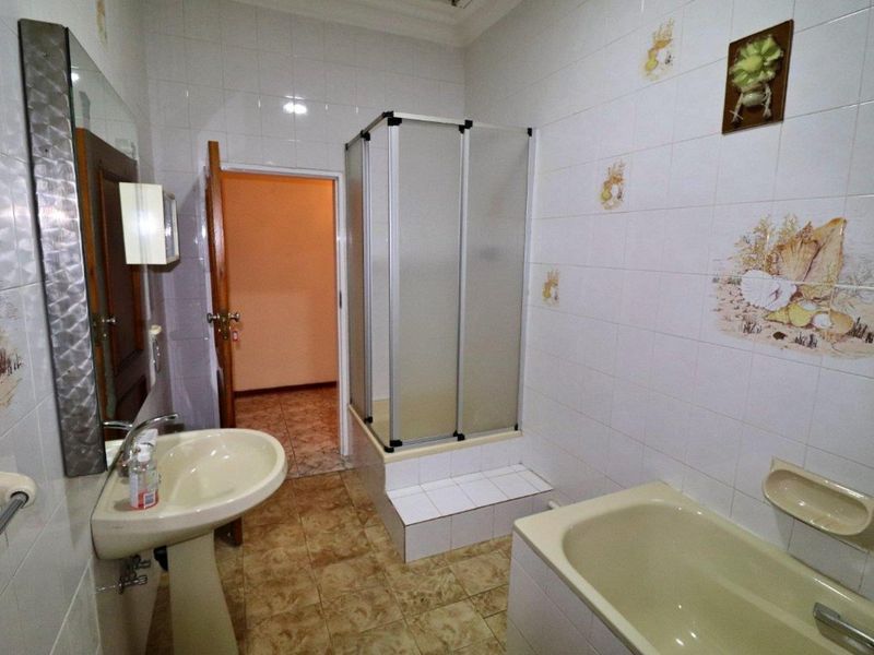 A dated bathroom featuring a pedestal basin, a built-in bathtub, and a separate shower cubicle with tiled walls and flooring.