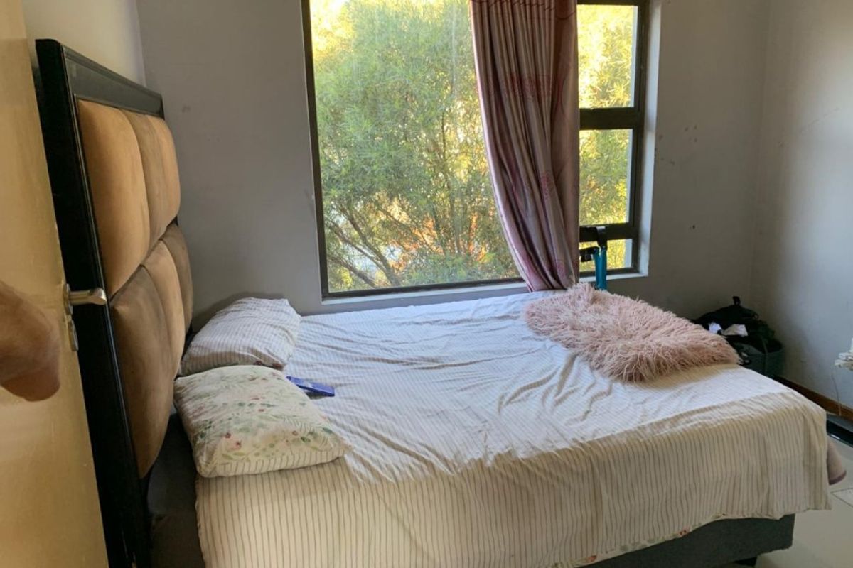 A bedroom featuring a large window with natural light, neutral wall finishes, and tiled flooring.
