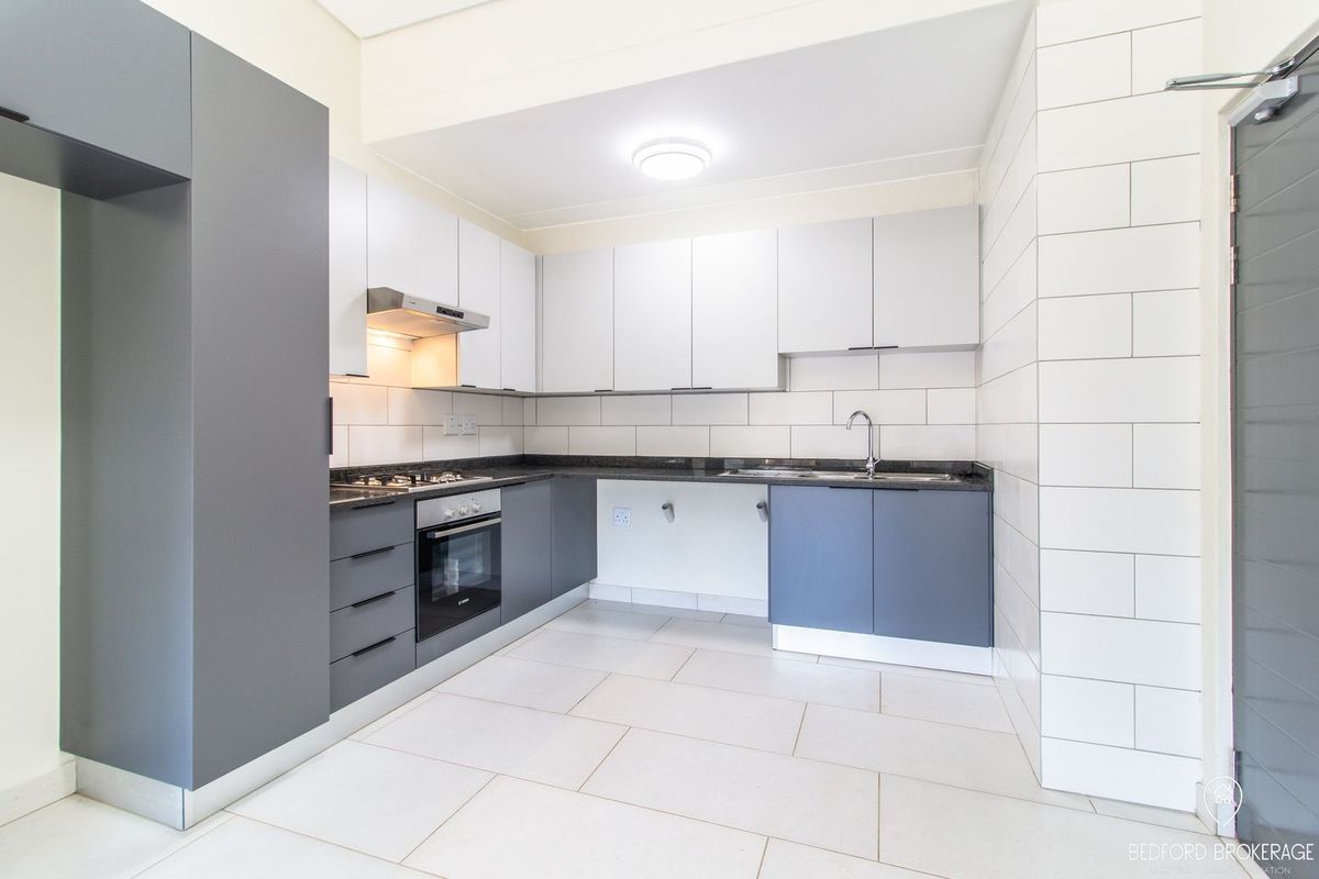 Modern kitchen featuring sleek grey and white cabinetry, granite countertops, built-in oven, gas hob, and a tiled splashback in a clean, contemporary finish.