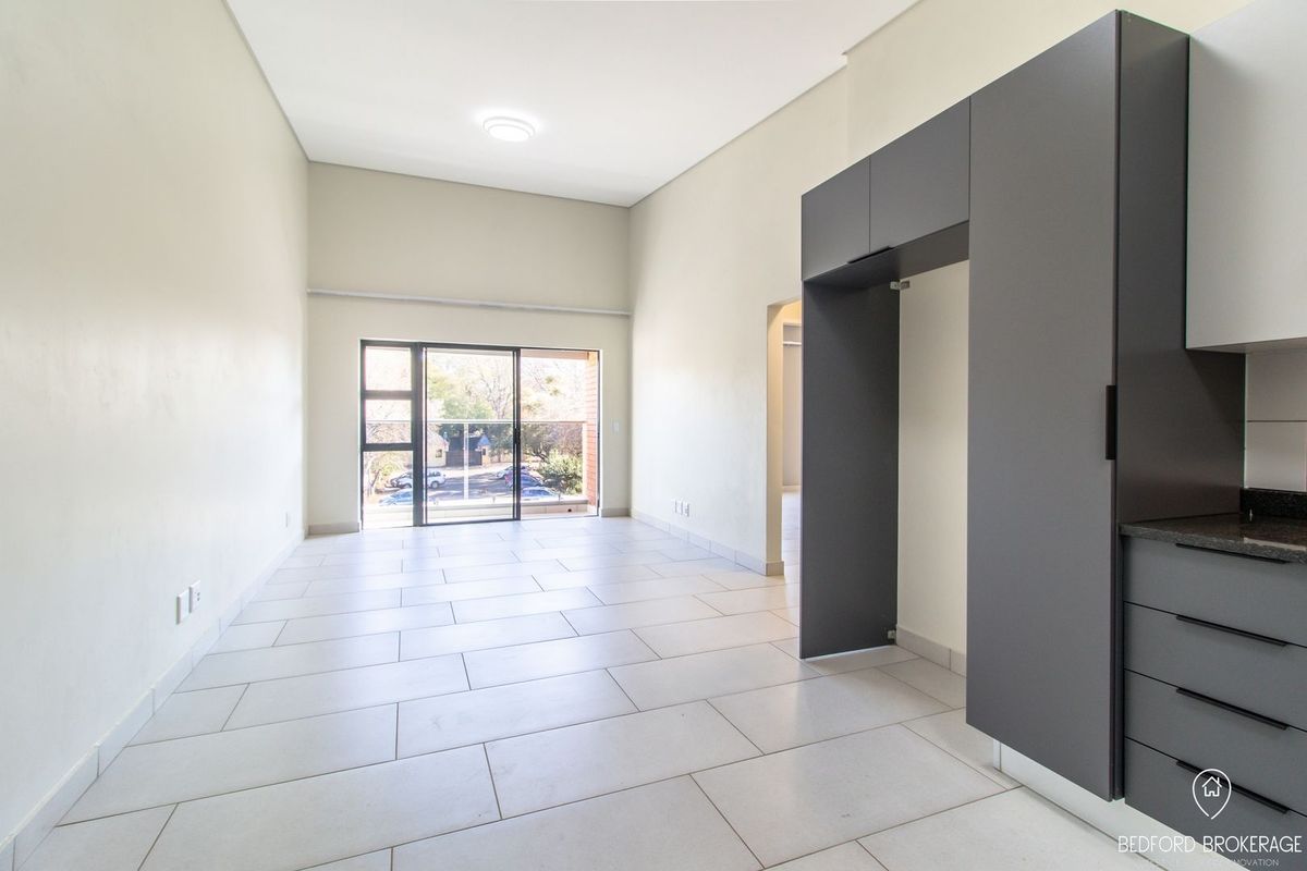 Spacious open-plan living area featuring modern grey cabinetry, granite countertops, and large sliding glass doors leading to a balcony.