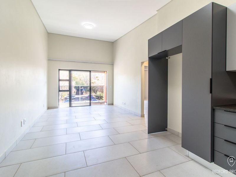 Spacious open-plan living area featuring modern grey cabinetry, granite countertops, and large sliding glass doors leading to a balcony.