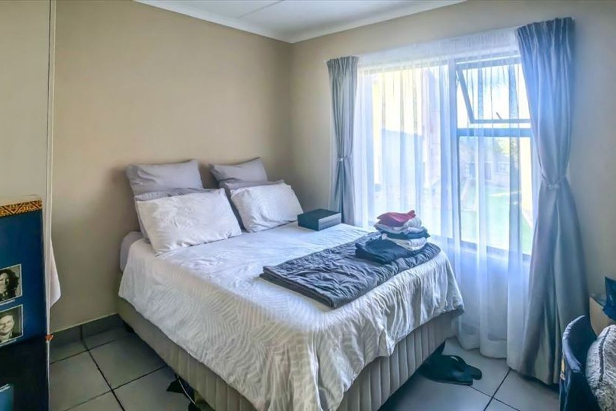 A functional bedroom featuring tiled flooring and a large window that allows for natural light.