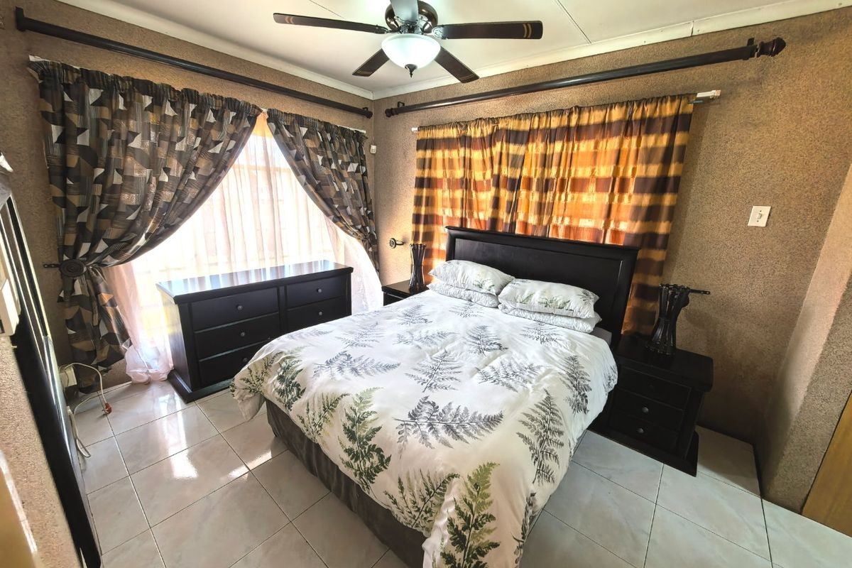 A bedroom featuring tiled flooring and a ceiling fan, offering a functional space with neutral wall finishes.