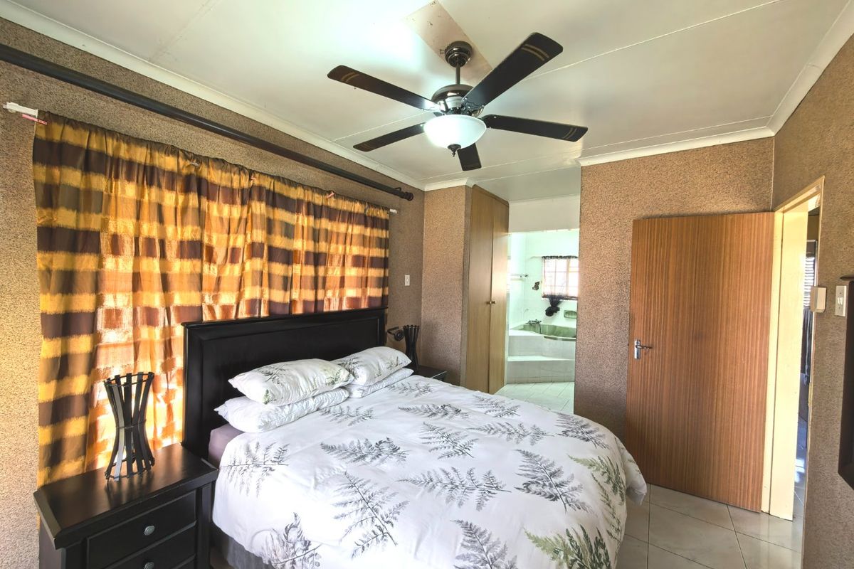 A bedroom featuring tiled flooring, a ceiling fan, and built-in wardrobe, with direct access to an en-suite bathroom.