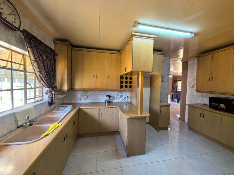 A functional kitchen featuring extensive laminate cabinetry, a double basin sink, tiled backsplash, and ceramic flooring, offering a classic layout with ample storage space.