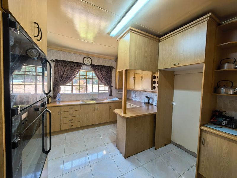 A functional kitchen featuring wood-look cabinetry, built-in wall ovens, tiled flooring, and ample counter space, offering a classic layout ready for modern updates.