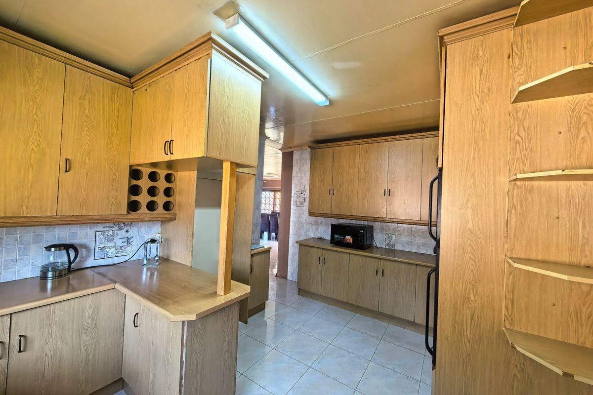 A functional kitchen featuring extensive laminate cabinetry, tiled backsplash, and ceramic flooring, offering a dated aesthetic with potential for modern renovation.