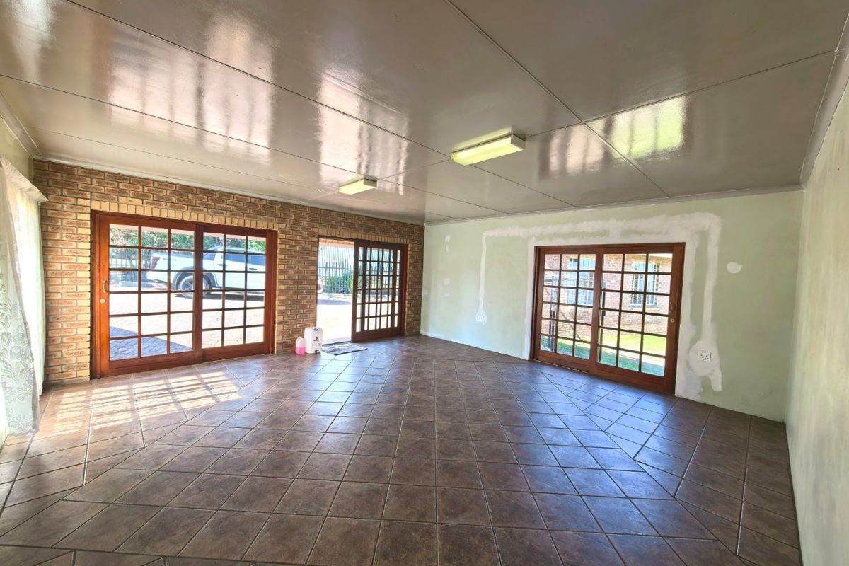 Spacious living area featuring tiled floors, exposed brick accents, and multiple sliding glass doors providing access to the exterior.