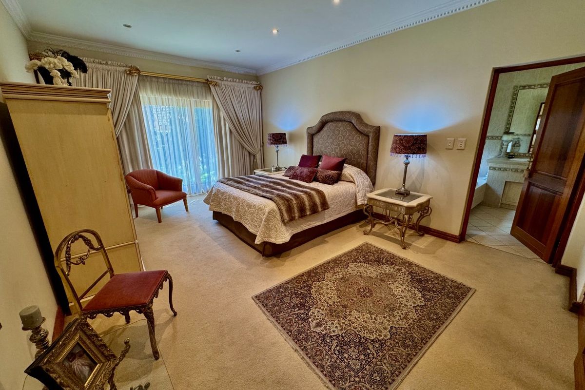 Spacious bedroom featuring neutral carpeting, recessed lighting, and direct access to an en-suite bathroom through a wooden door.