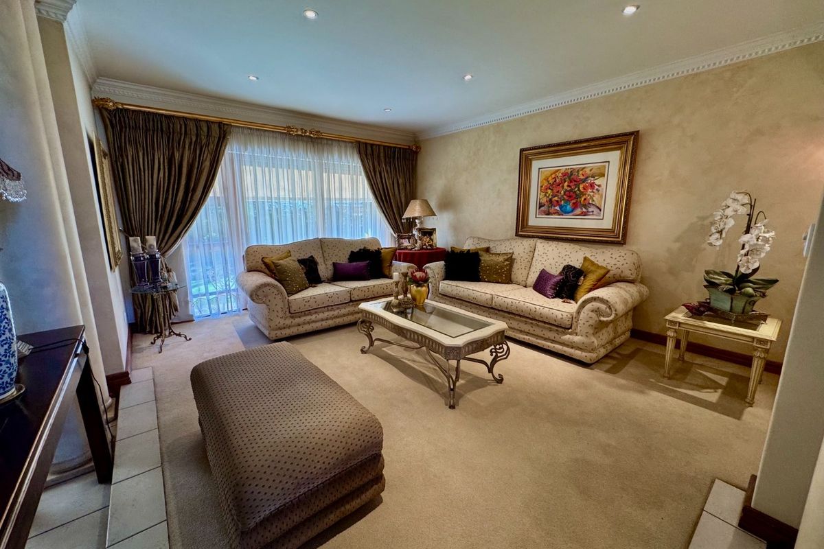 A comfortable living room featuring neutral carpet flooring, recessed downlighting, crown molding, and a large sliding glass door providing access to the exterior.