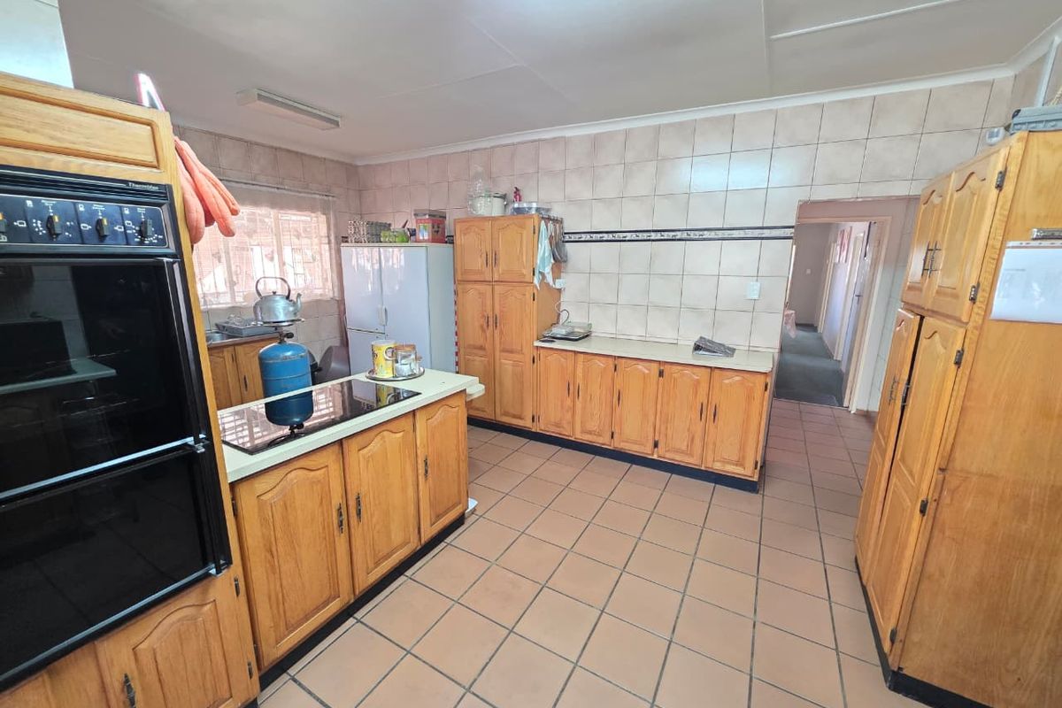 A functional kitchen featuring extensive wooden cabinetry, tiled flooring, a built-in oven, and a tiled backsplash, offering a traditional layout with ample storage space.