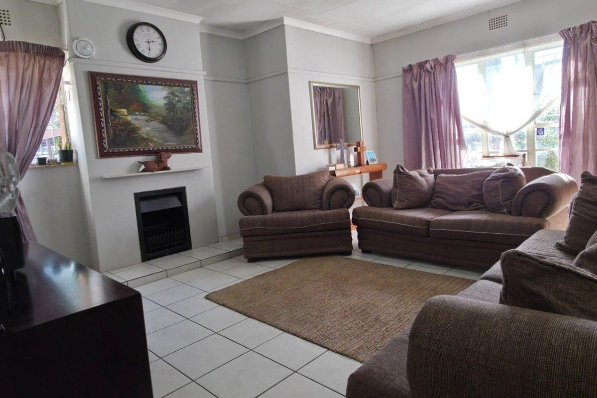 A comfortable living room featuring a built-in fireplace, tiled flooring, and classic cornicing, offering a functional and inviting space for relaxation.