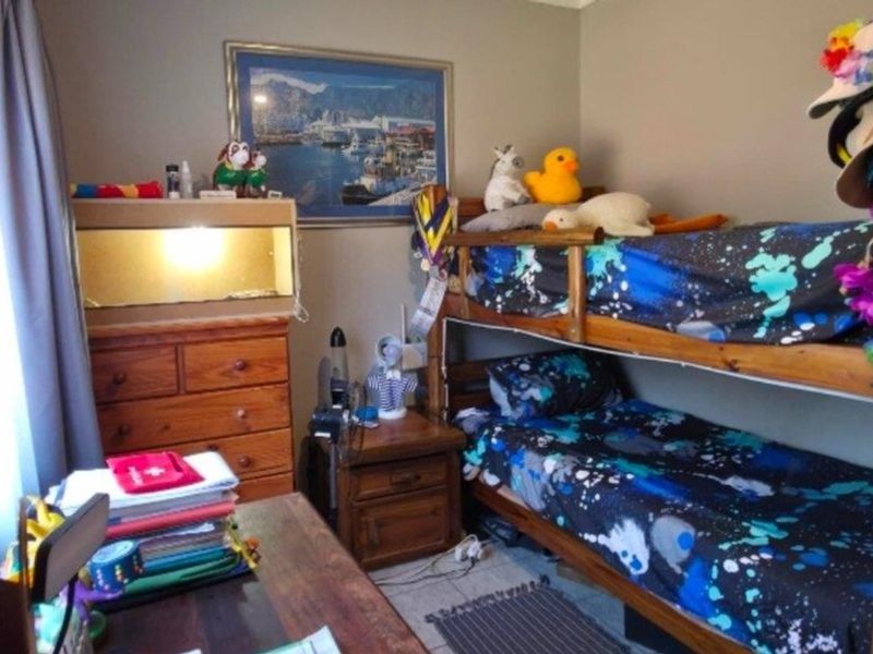A functional bedroom featuring tiled flooring and neutral wall tones, currently utilized as a children's room.