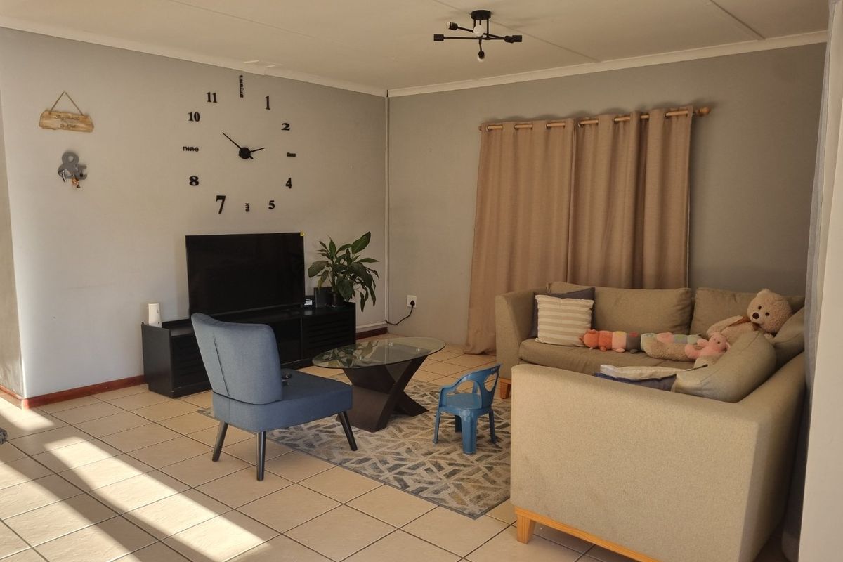 A living room featuring tiled flooring and a central ceiling light fixture, providing a functional and neutral space for relaxation.